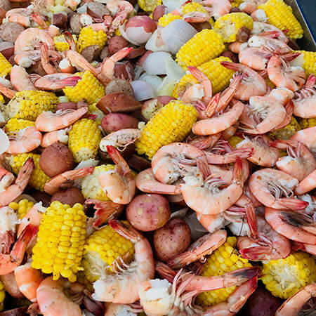A large tray filled with crawfish, corn, and potatoes, showcasing a colorful and appetizing lowcountry seafood boil