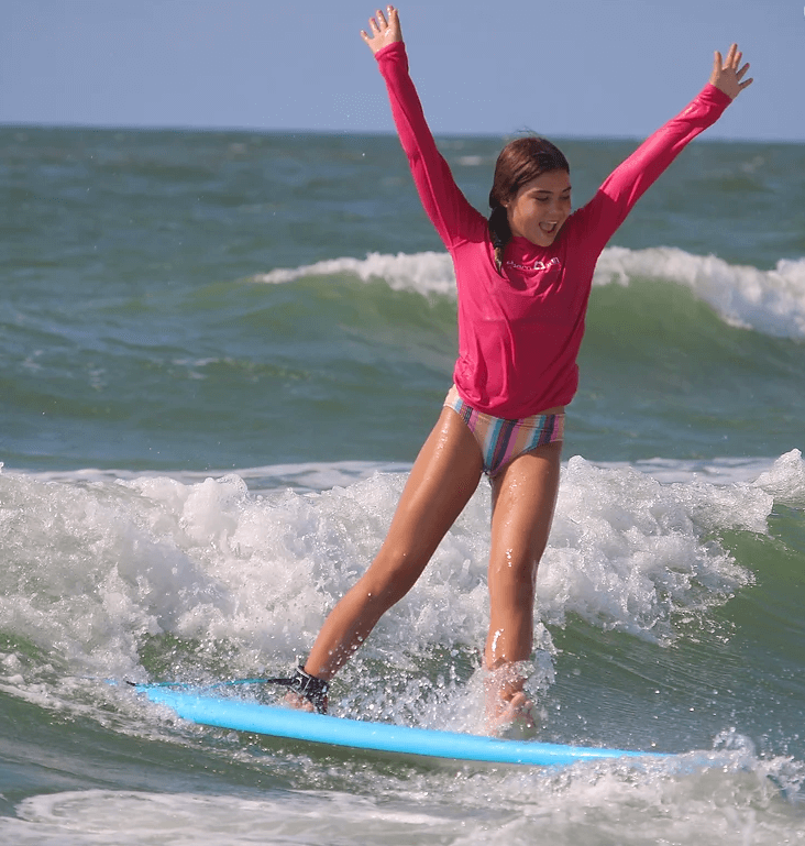 Girl riding wave and cheering-onlypawleys