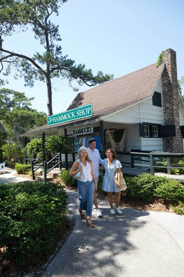 People walking in front of a white building labeled "The Original Hammock Shop" on Pawleys Island