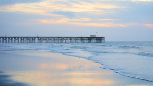 Gentle waves lap the shore at twilight with the Pawleys Island Pier in the distance.